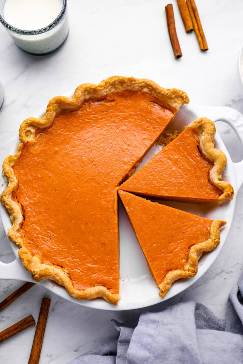 overhead view of a partially sliced sweet potato pie in a white pie pan with handles.