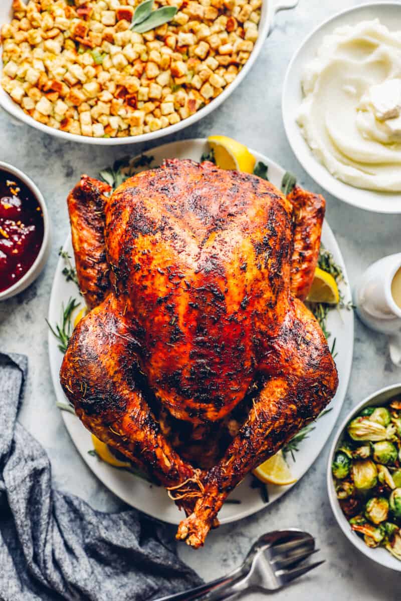 whole roast thanksgiving turkey at the center of a table, surrounded by side dishes