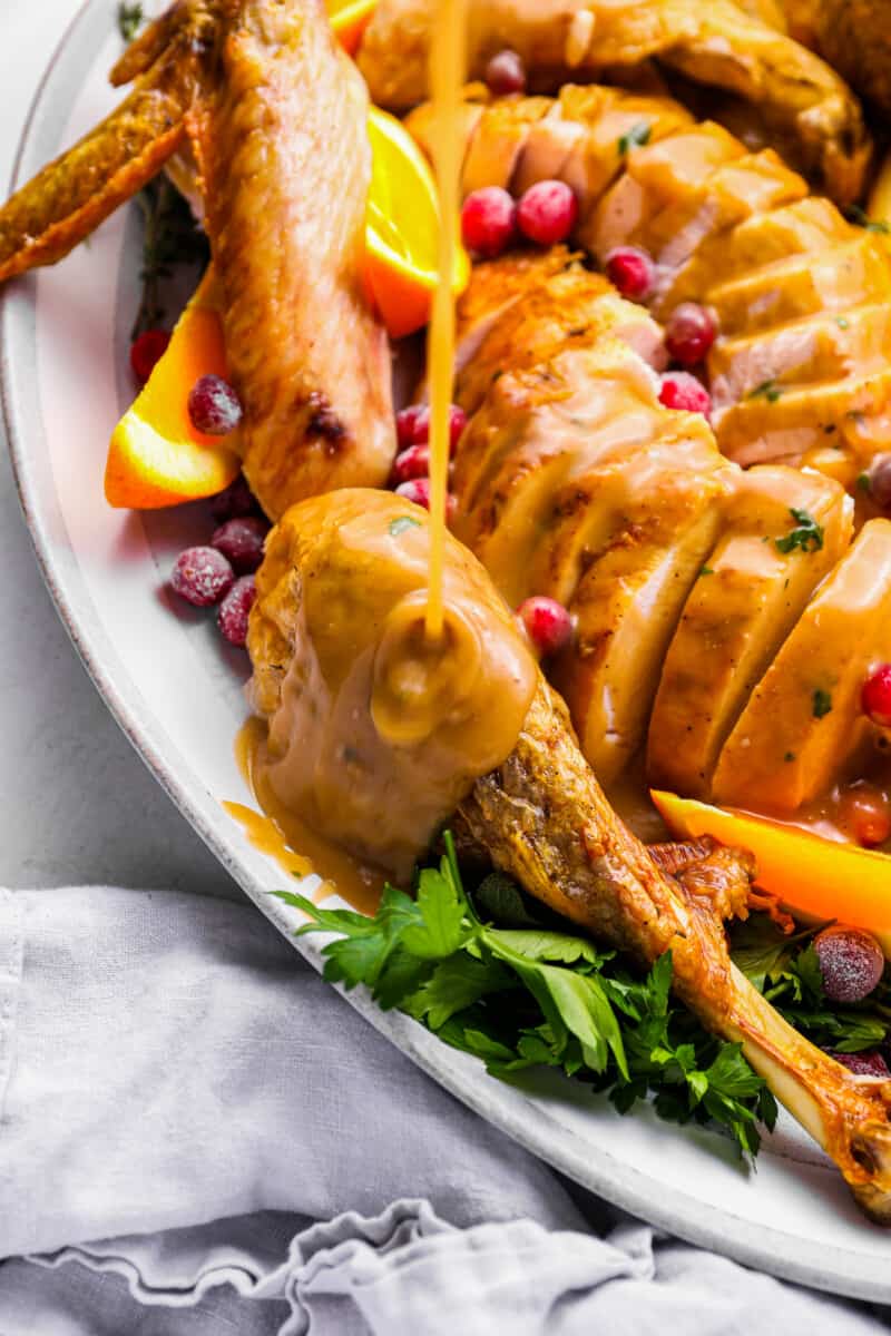 turkey gravy on top of a sliced whole turkey on a white plate.