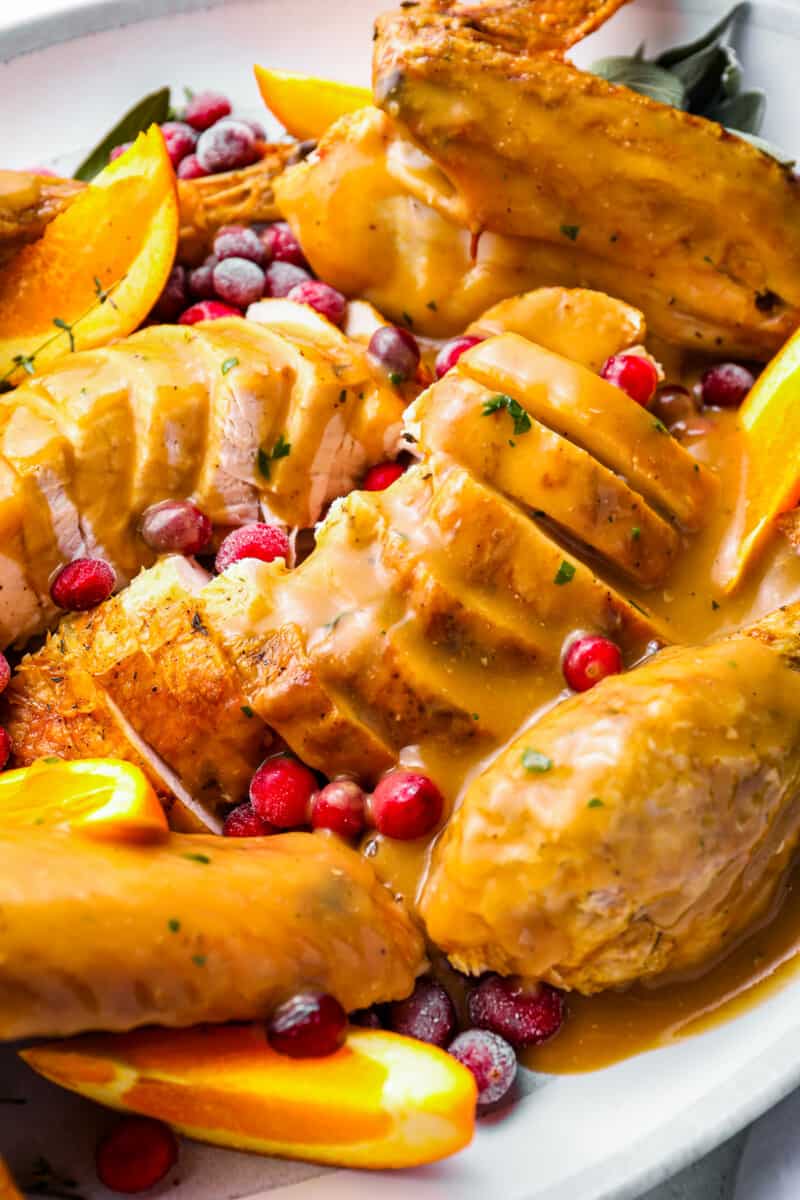 turkey gravy on top of a sliced whole turkey on a white plate.