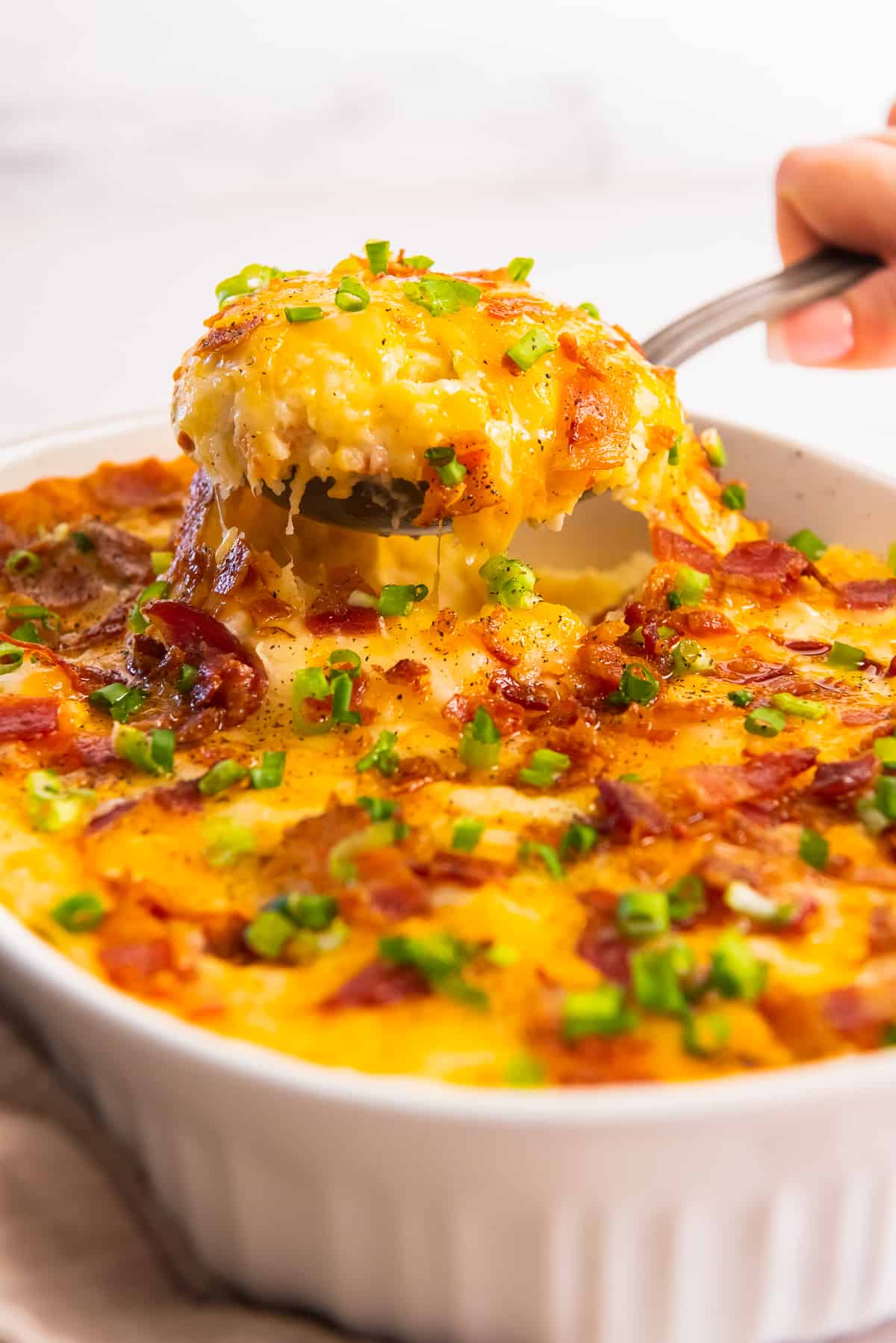 Scooping a serving of twice baked potato casserole.