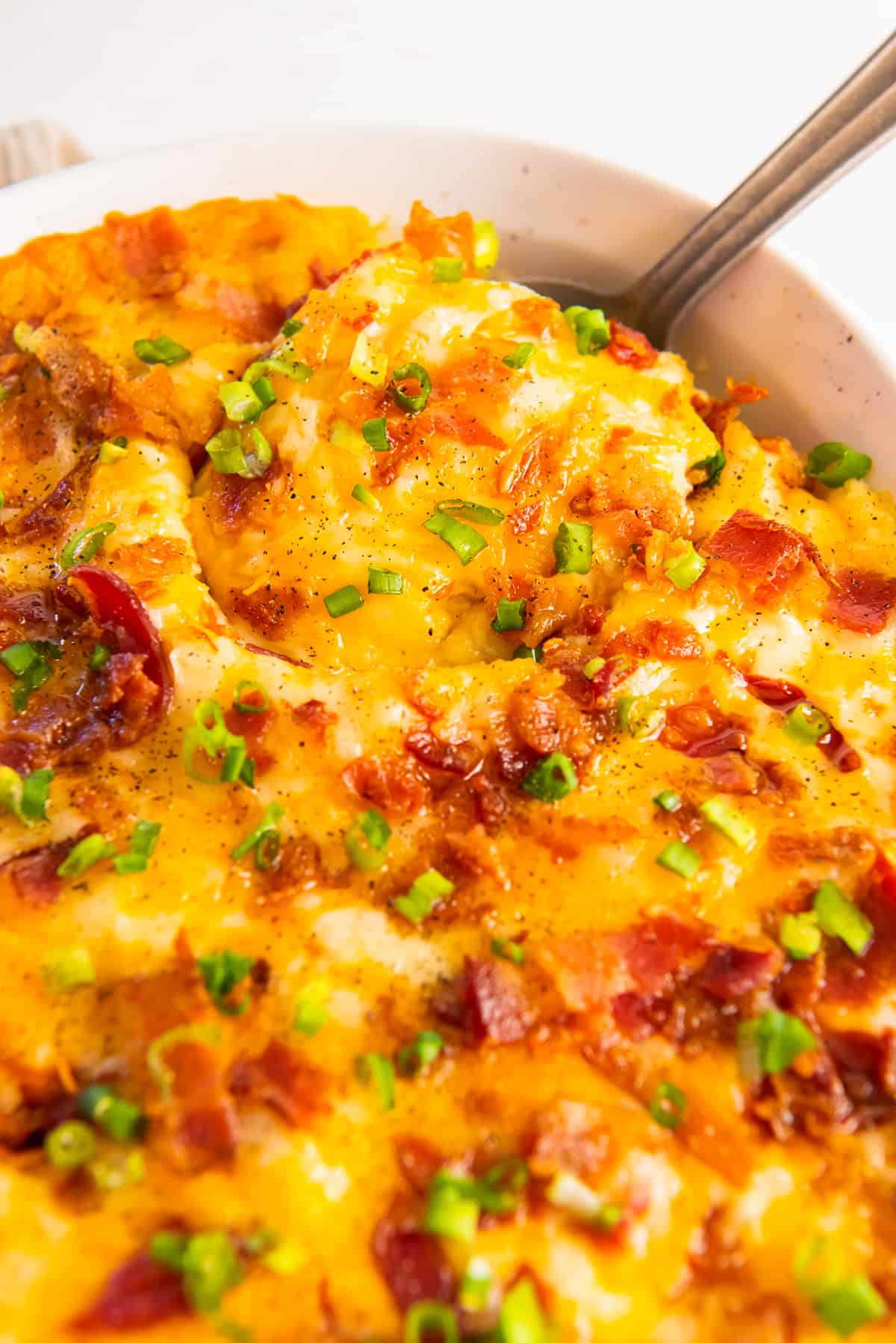 close up on potato casserole baked with cheese, bacon bits, green onions