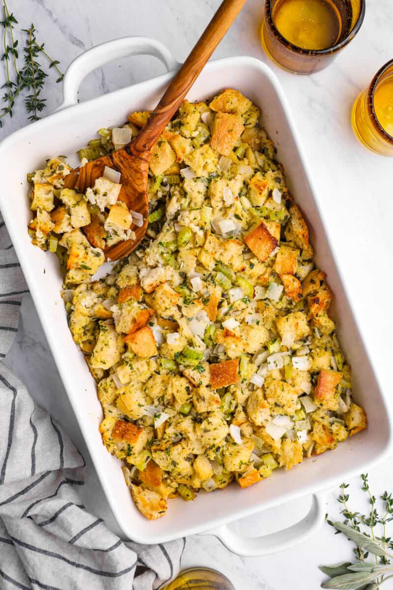 overhead view of vegetarian stuffing in a white baking dish with a wooden spoon.