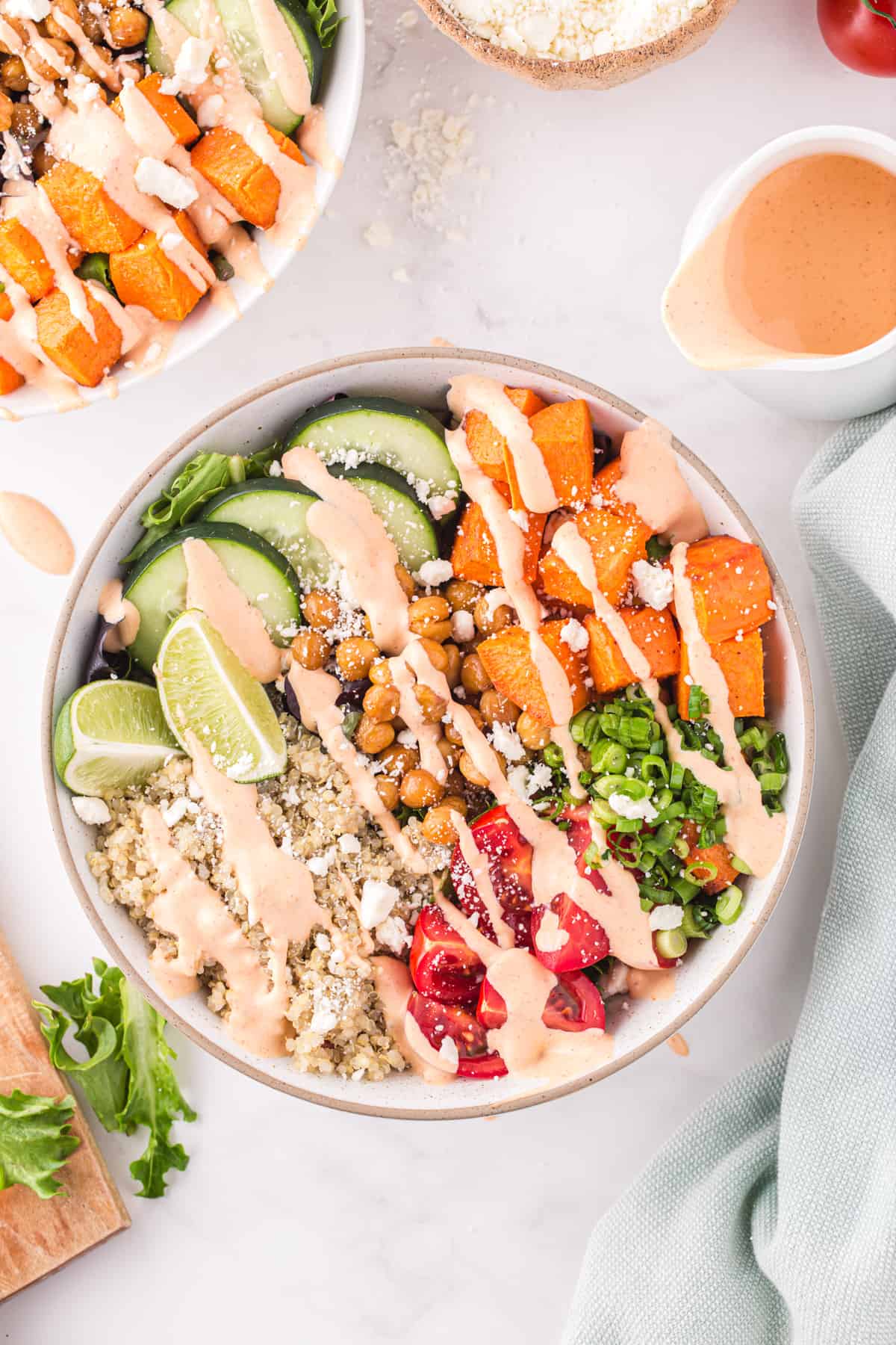 overhead view of a buddha bowl drizzled with sriracha mayo dressing in a white bowl.