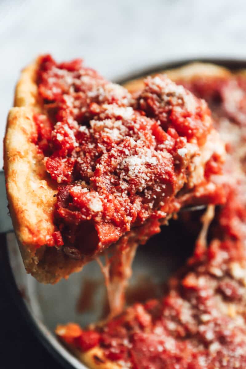 a pie server removing a slice of chicago deep dish pizza from a pan.