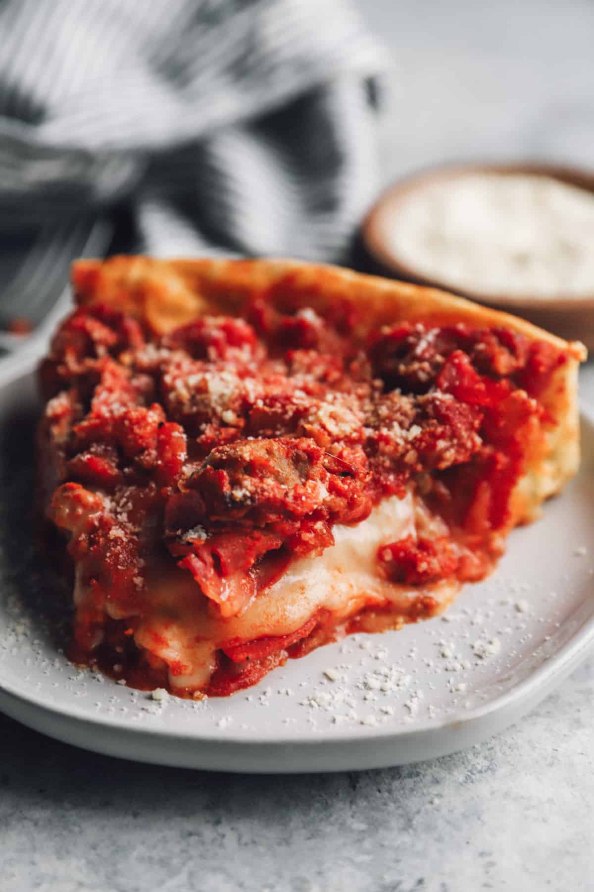 a slice of chicago deep dish pizza on a white plate.