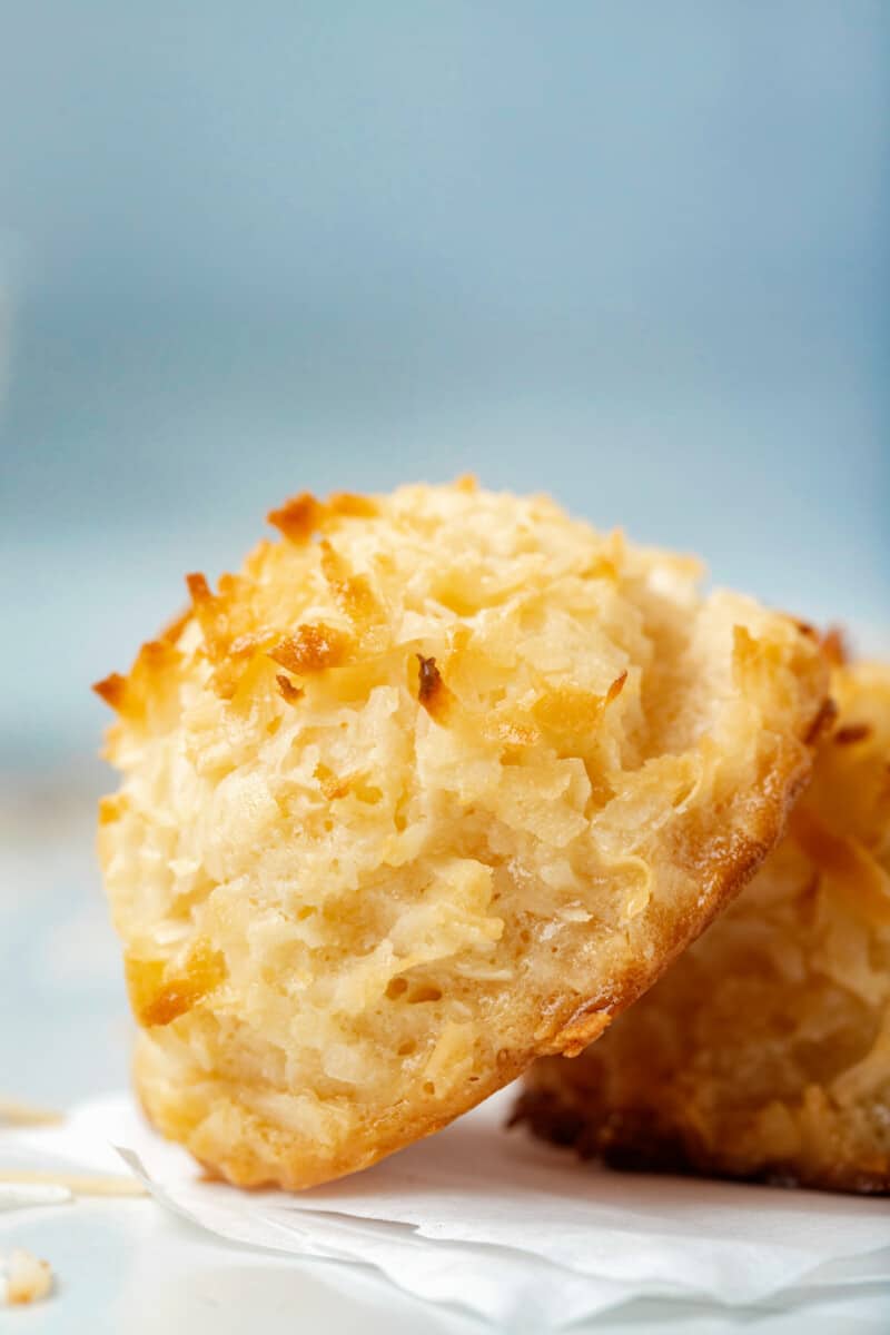 close up of a coconut macaroon leaning against another coconut macaroon.