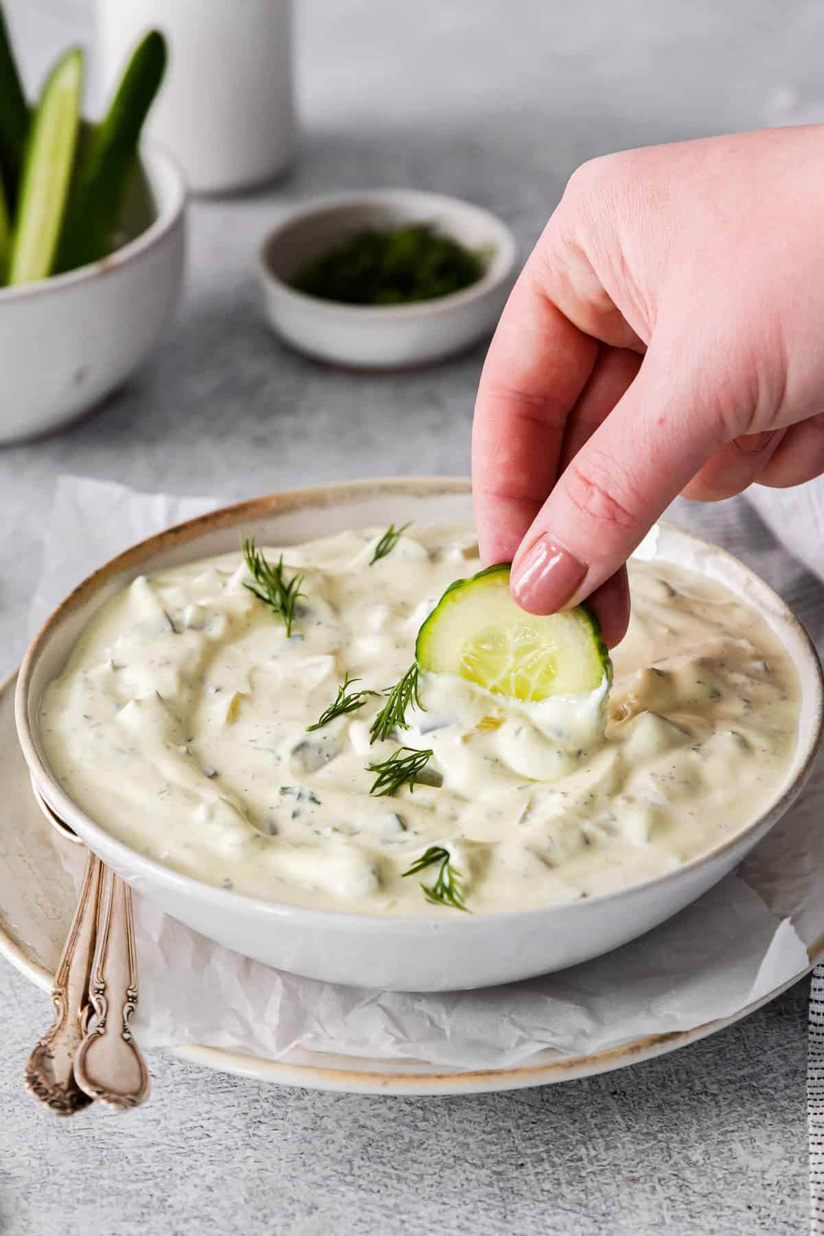 hand dipping a slice of cucumber into dip