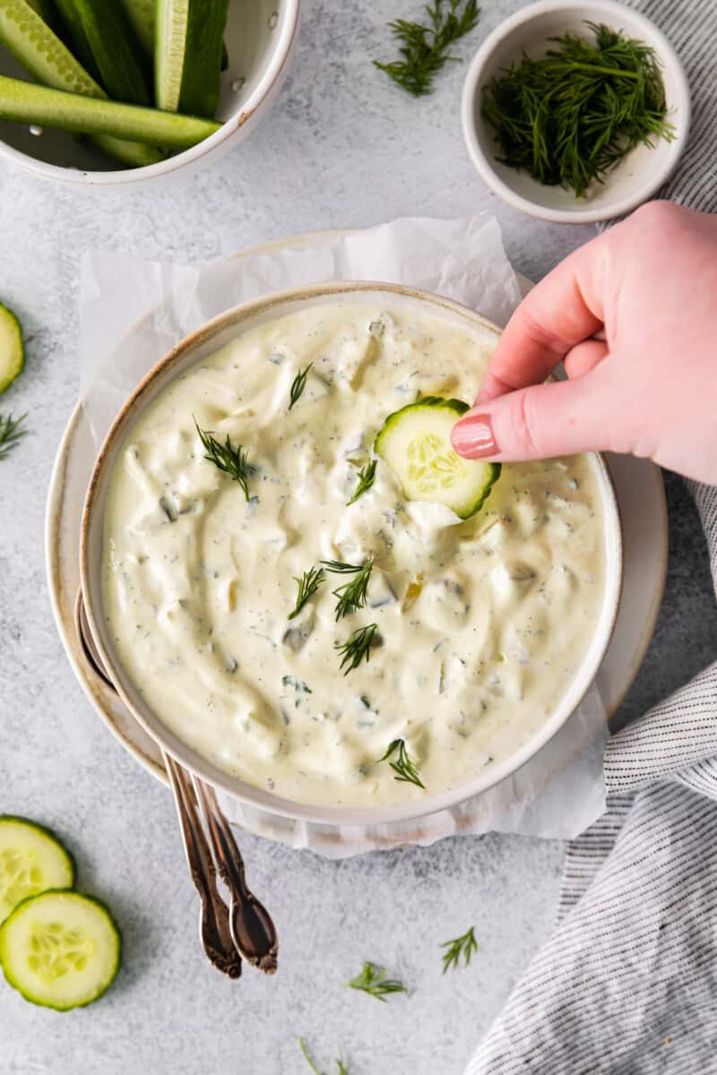 overhead view dipping cucumber into dill pickle dip