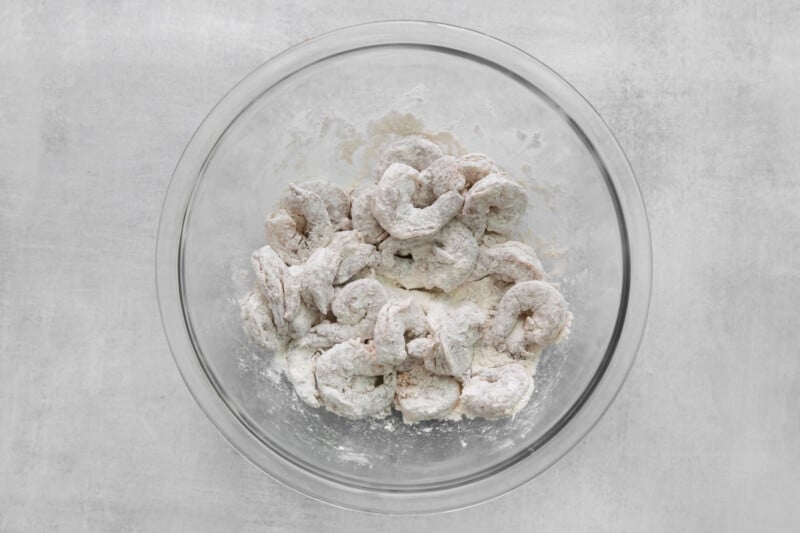 raw shrimp coated in flour and cornstarch in a glass bowl.