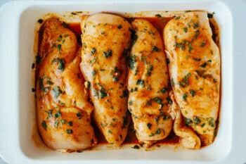 4 cilantro lime marinated raw chicken breasts in a rectangular baking pan.