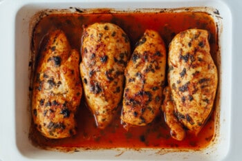 4 baked cilantro lime chicken breasts in a rectangular baking pan.