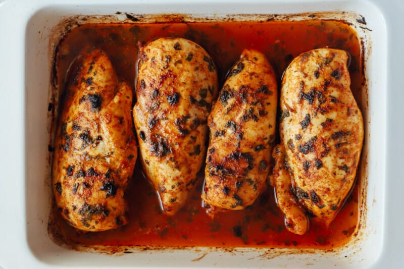 4 baked cilantro lime chicken breasts in a rectangular baking pan.