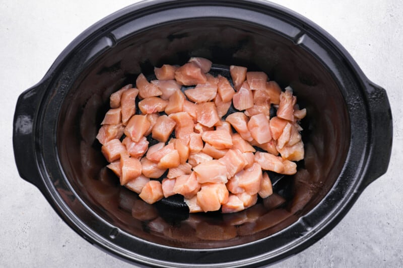 cubed raw chicken in a crockpot.