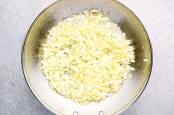 onions sizzling in a stainless frying pan.