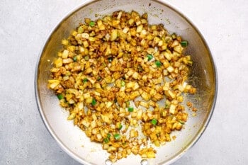 crispy onions and spices in a stainless frying pan.