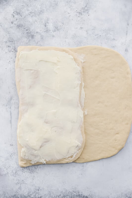 cronut dough folded in thirds and buttered on a marble counter.