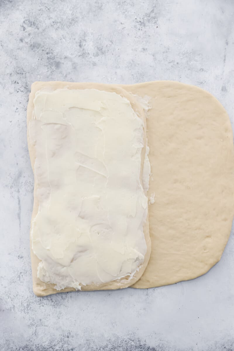 Cronut dough folded in thirds and buttered on a marble counter.
