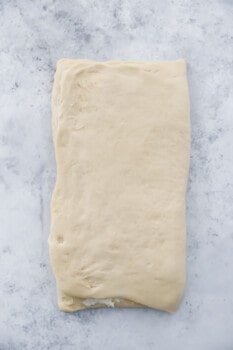 folded cronut dough on a marble counter.