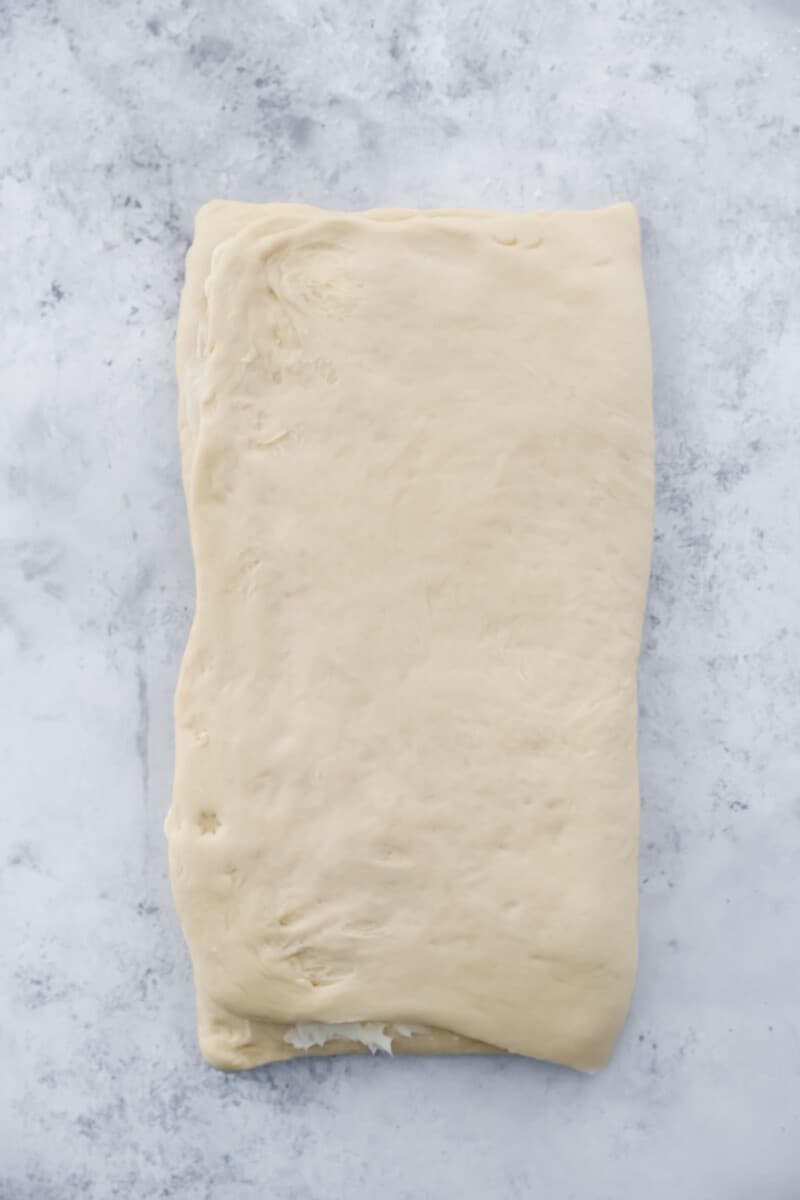 Folded cronut dough on a marble counter.