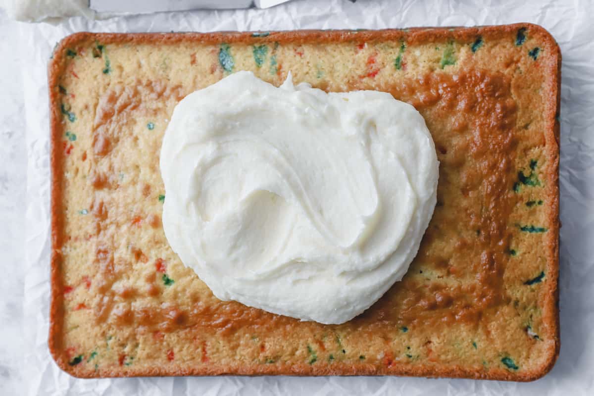 frosting being spread over a baked funfetti cake.