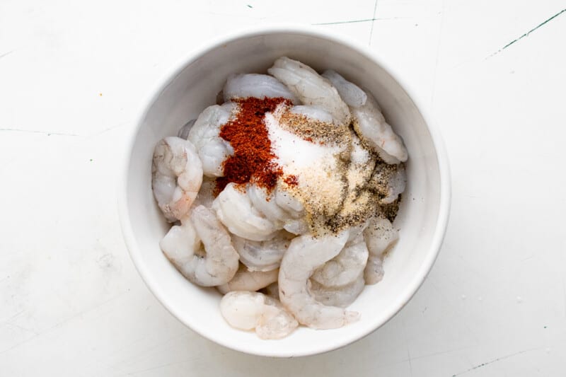 uncooked shrimp in a bowl with seasonings