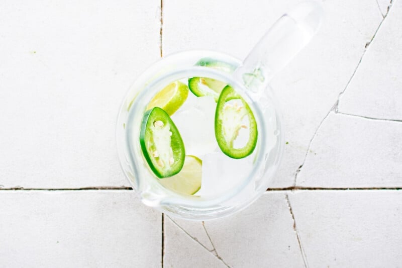 a pitcher of water with lime slices and jalapenos.
