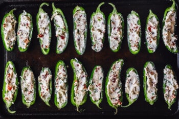 jalapeños stuffed with mixture lined up on a baking tray