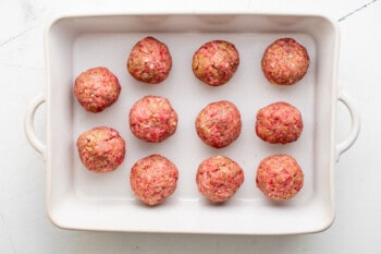 11 meatballs in a white baking pan.