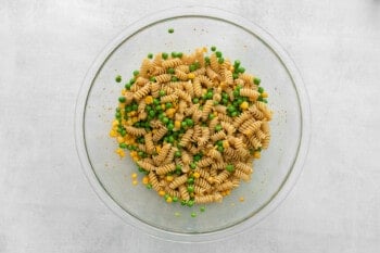 cooked pasta, peas, and corn in a glass bowl.