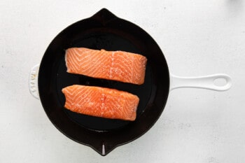 2 raw salmon filets skin side down in a cast iron skillet.