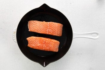 2 raw salmon filets skin side down in a cast iron skillet.