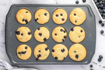 12 baked blueberry pancake muffins in a muffin tin.