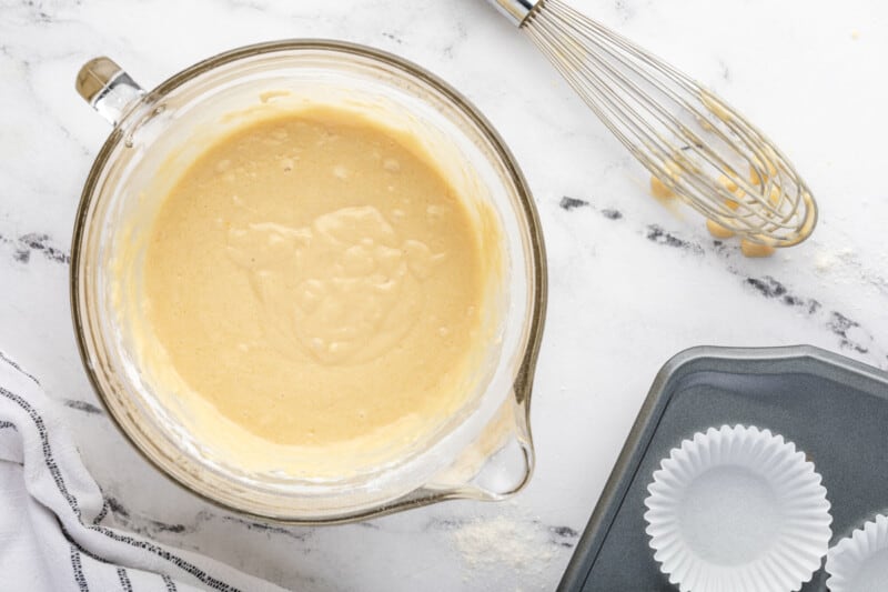 blueberry pancake muffin batter in a glass bowl with a whisk.