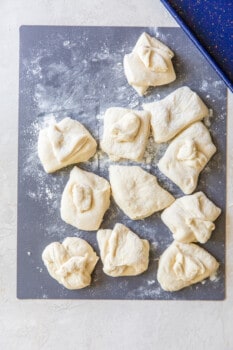 olive garden breadstick dough portioned into 11 dough balls on a black cutting board.