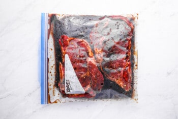 2 ribeyes marinating in a sealed ziplock bag.