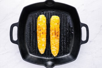 overhead view of 2 ears of corn in a cast iron grill pan.