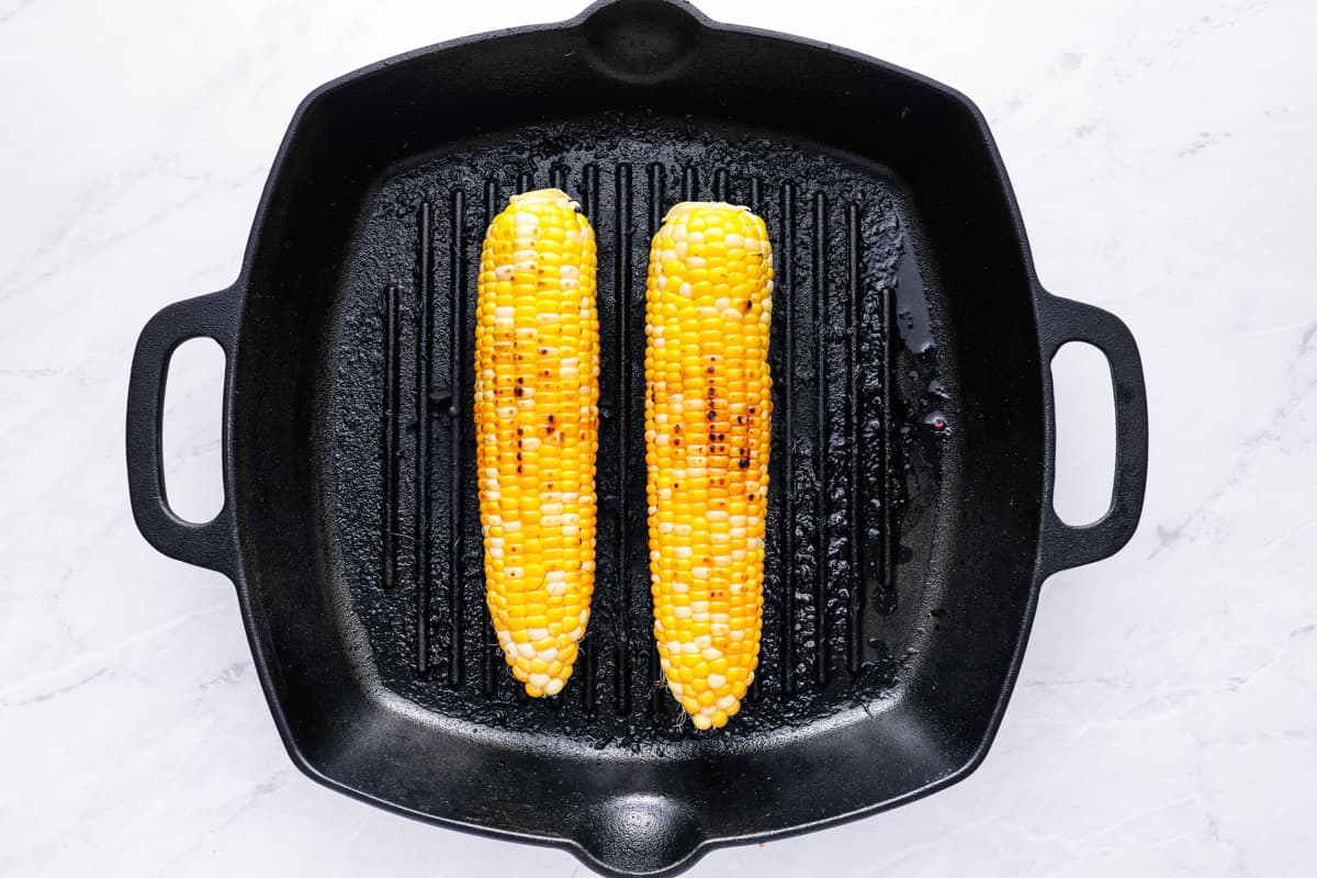 Overhead view of 2 ears of corn in a cast iron grill pan.