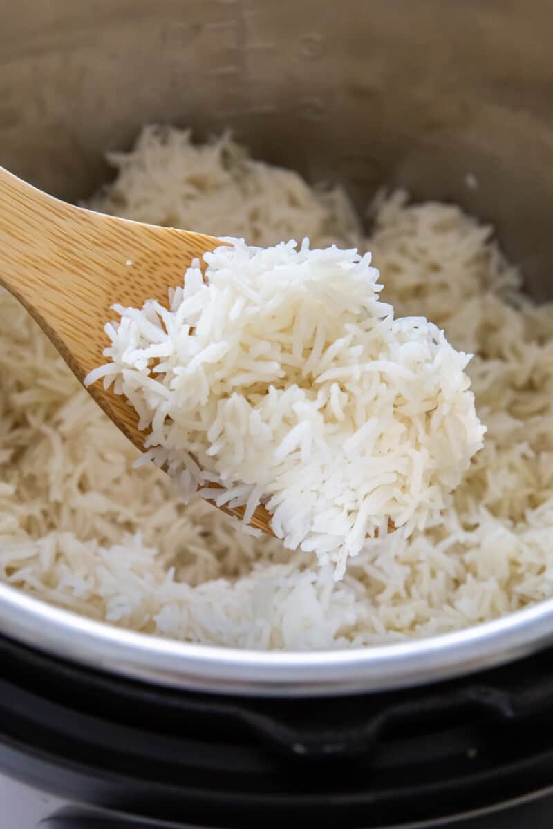 a spoon lifting a scoop of instant pot basmati rice from an instant pot.