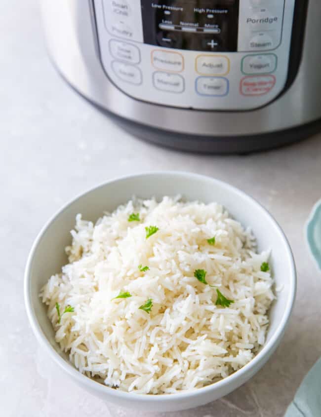 instant pot basmati rice in a white bowl next to an instant pot.