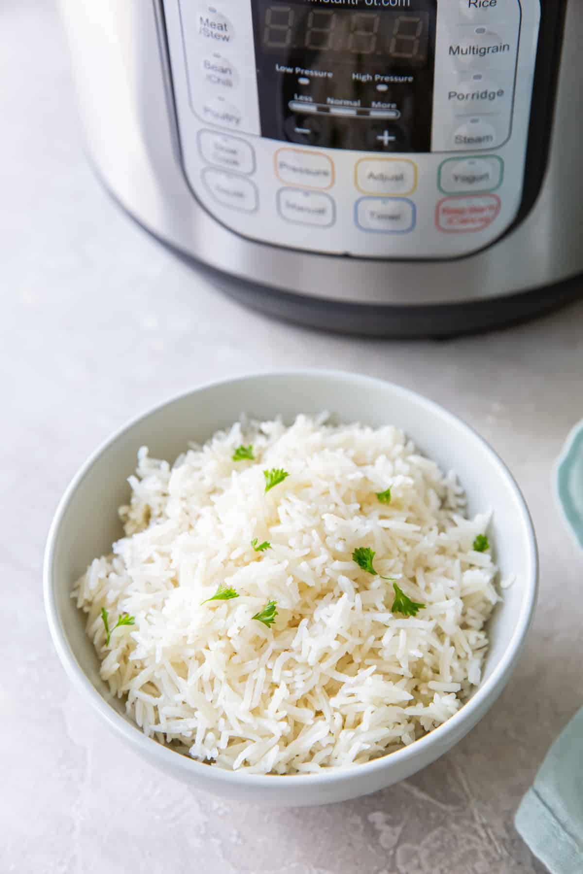 instant pot basmati rice in a white bowl next to an instant pot.