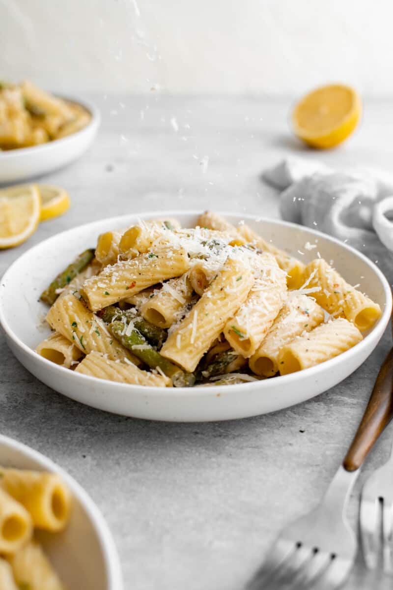 shallow bowl full of pasta with asparagus on a tablescape
