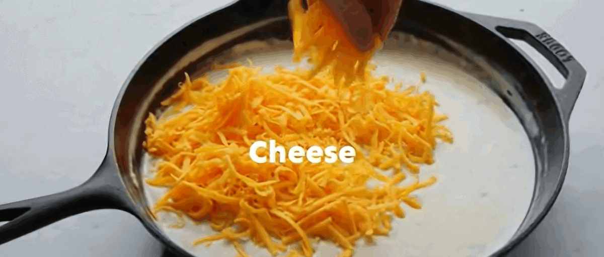 Adding cheese to the skillet with the milk and sour cream mixture. 