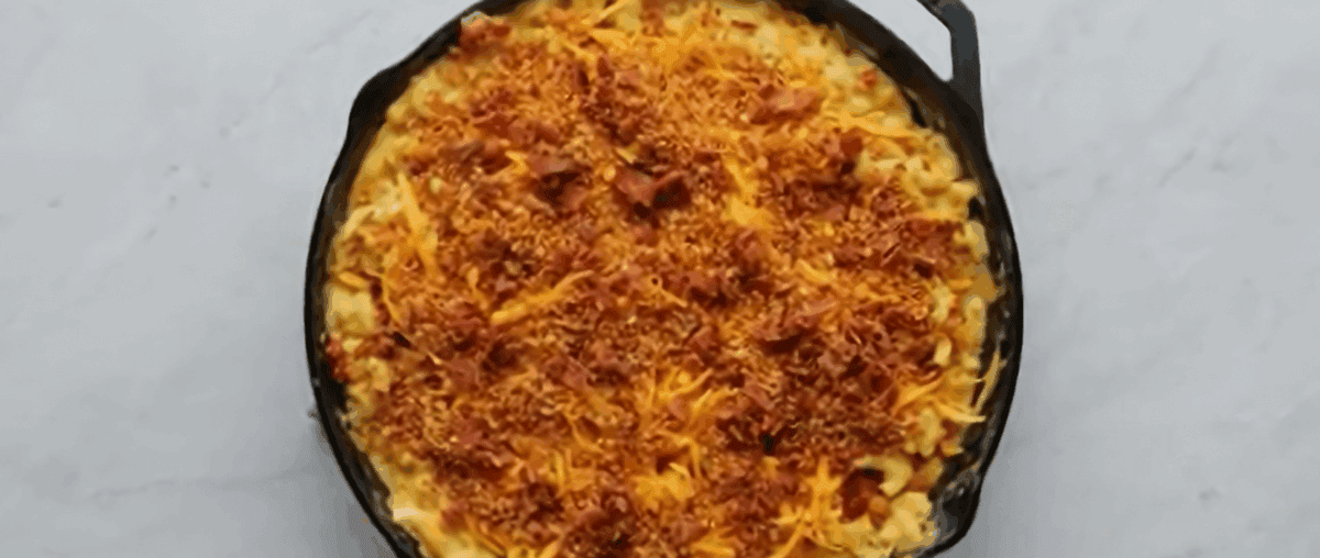 Mac and cheese in a skillet topped with toasted breadcrumbs, bacon and cheese.