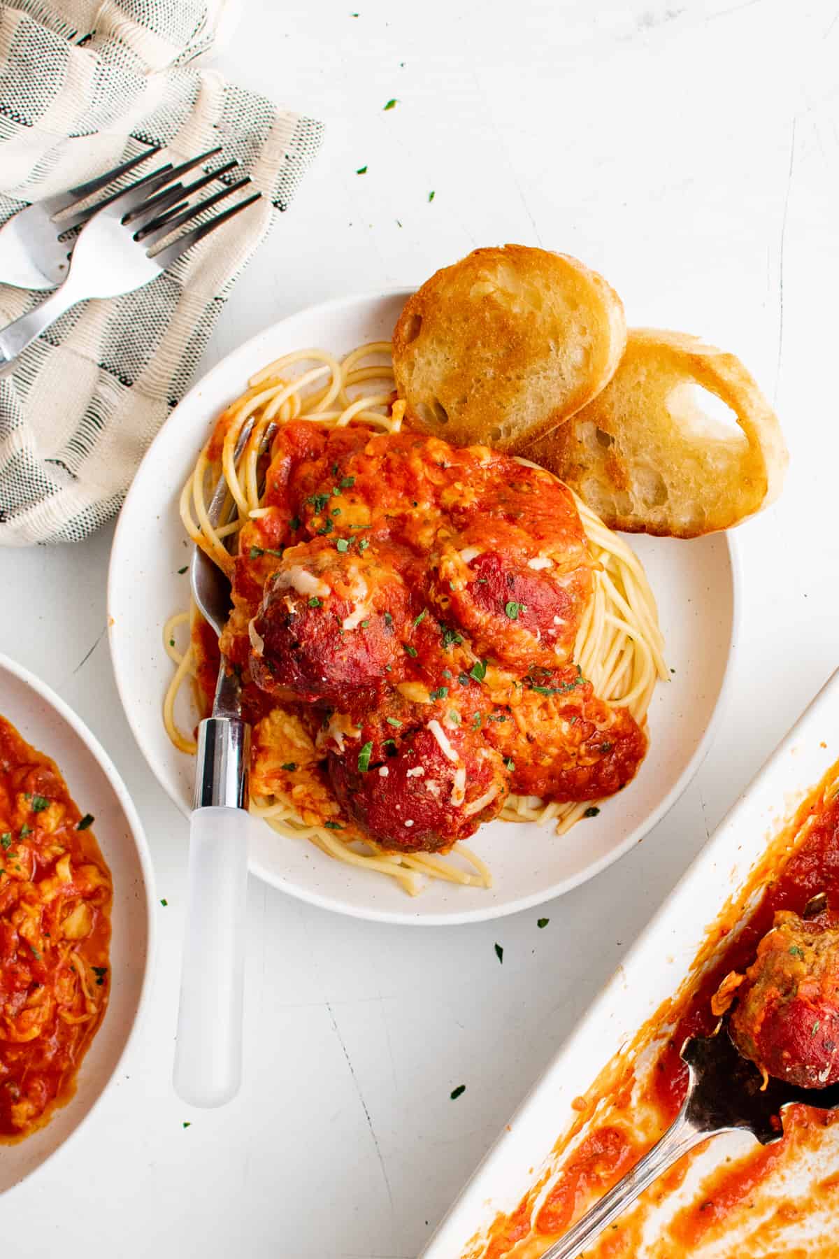 a plate of spaghetti and meatballs casserole on a plate, surrounded by more bowls and serving dishes.