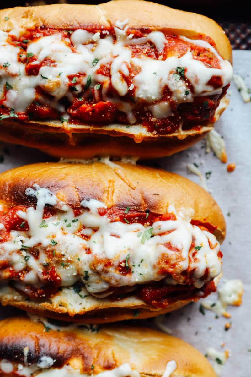 close up of meatball subs on a lined baking sheet.