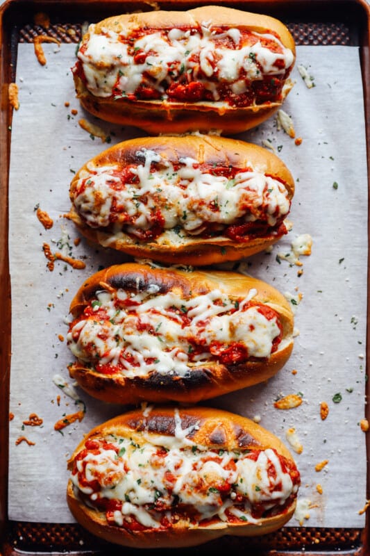 overhead view of meatball subs on a lined baking sheet.