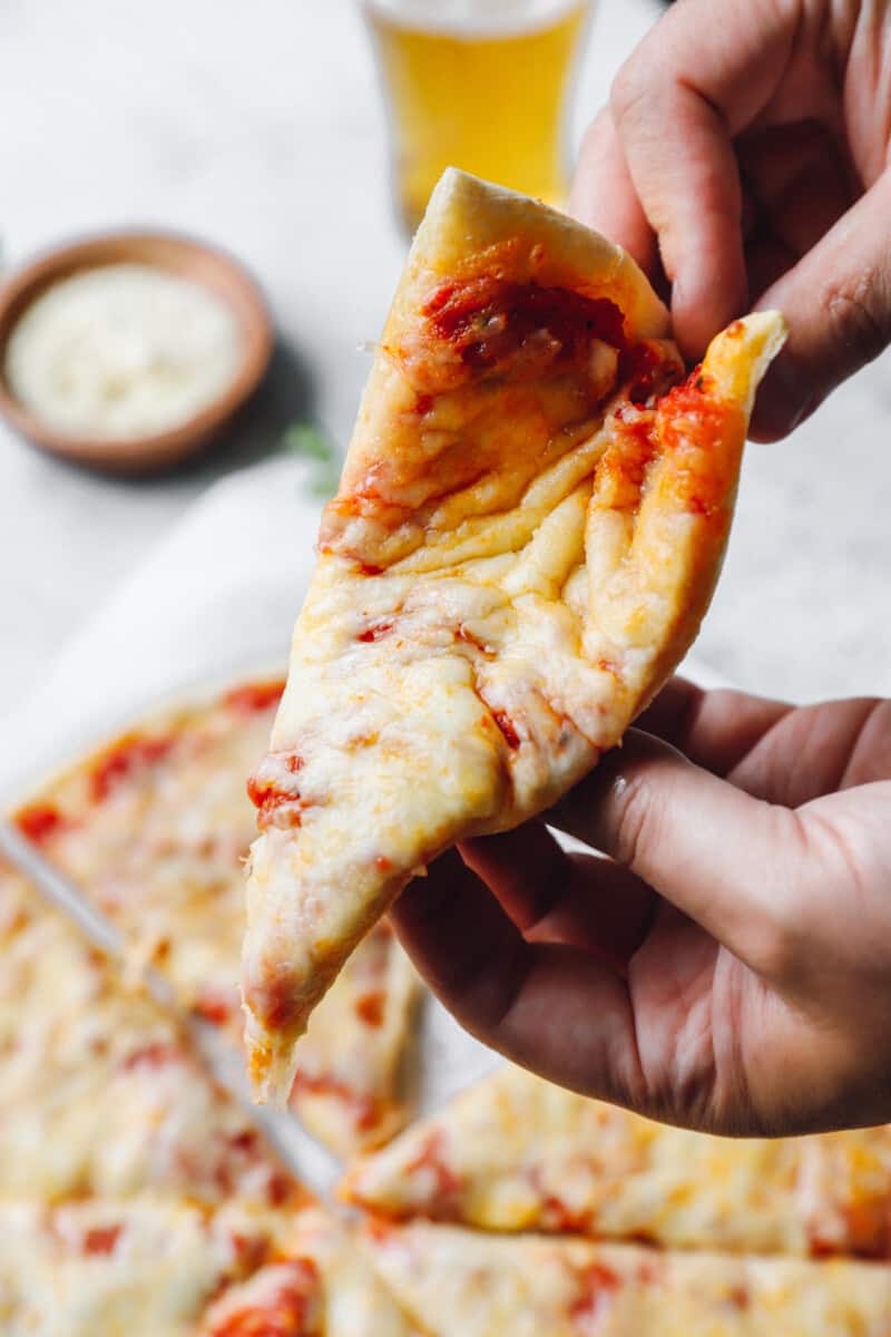 hands folding a slice of new york style pizza.