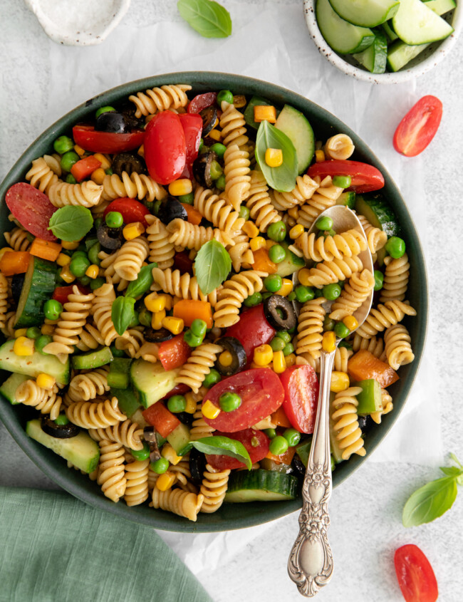 overhead view of veggie pasta salad in a gray bowl with a spoon.