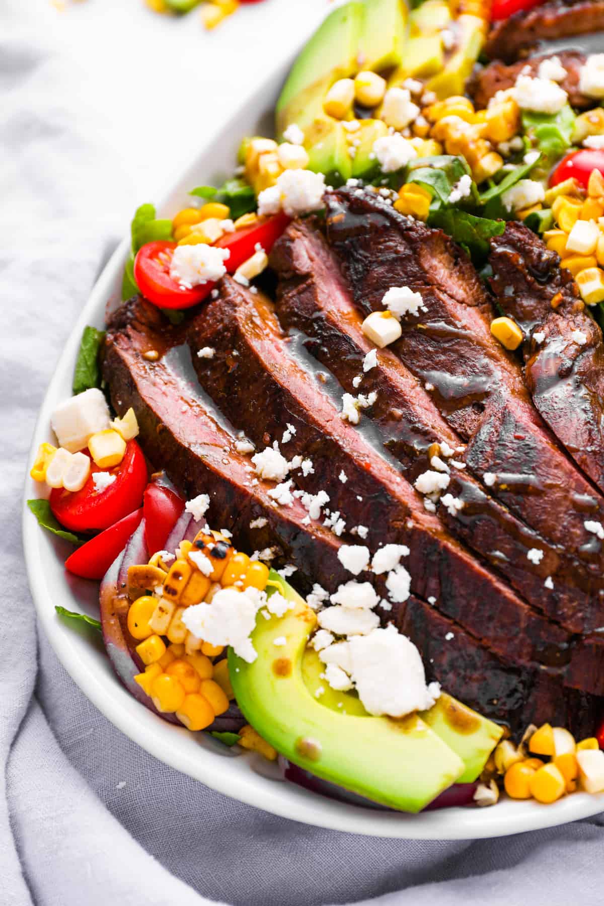 partial overhead view of steak salad in a white oval serving platter.